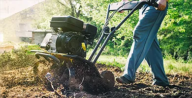 Person arbeitet mit Gartengerät auf Erde